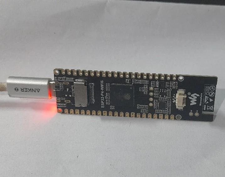 An ESP32 development board connected by USB with a red indicator light